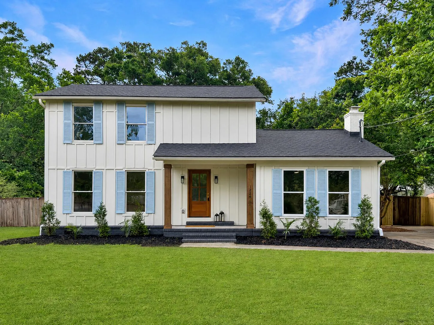 Two-story white modern farmhouse with cedar porch posts and deep green lawn