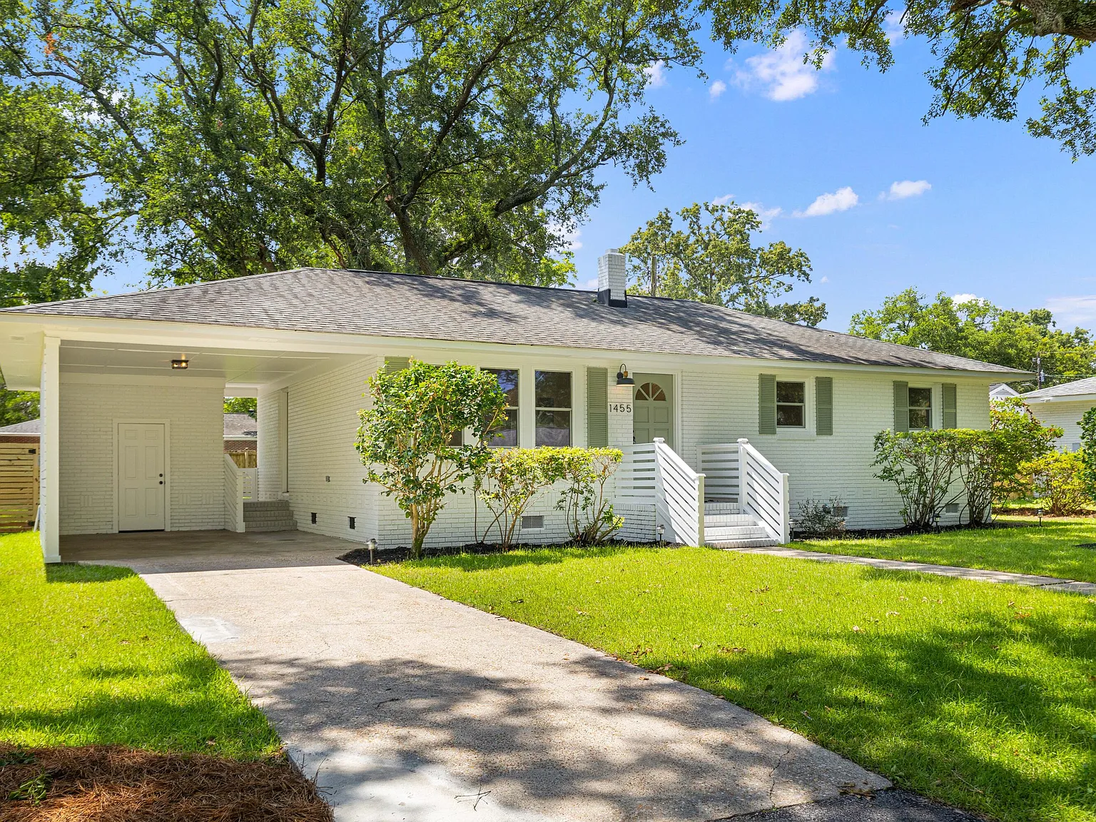 Crisp white mid-century Charleston ranch under live oaks