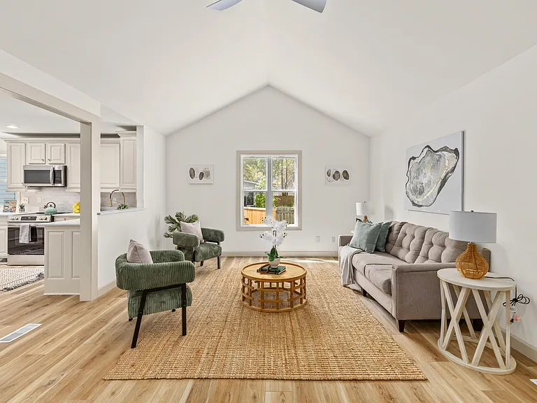 Sunlit vaulted living room with gray sofa, green chairs and jute rug