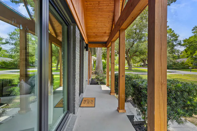 Covered porch with a warm cedar tongue-and-groove ceiling, cedar posts, and floor-to-ceiling glass looking out to the lawn.